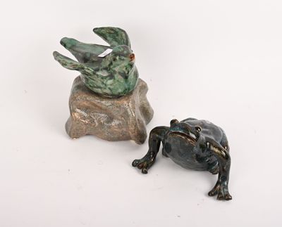 statue d'une grenouille assise sur un rocher, à côté d'une autre statue de grenouille