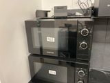 three microwaves stacked on top of each other in a kitchen