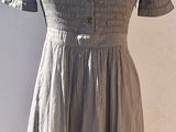 grey dress on a mannequin stand against a white wall