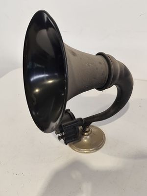 un vieux cor noir et argent posé sur une table blanche