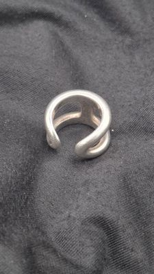 un gros plan d'une bague en argent posée sur un tissu noir
