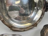 a silver bowl sitting on top of a table next to other silver dishes