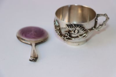 une tasse en argent et une cuillère posées sur une table