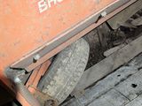 a small orange truck with a big tire underneath it