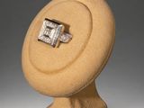 an image of a diamond ring sitting on top of a wooden stand