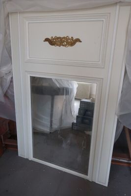 un miroir placé dans le coin d'une cheminée, orné d'un décor doré