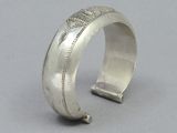 a close up of a silver bracelet on a gray surface