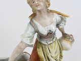 a figurine of a woman holding a pot and a stick