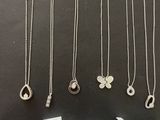 a collection of silver necklaces and pendants on a table
