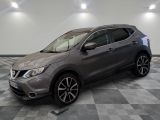 un SUV Nissan gris garé sur un sol en damier dans un garage