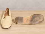 pair of beige shoes on wooden surface with white wall in background