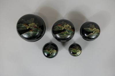 quatre bols noirs ornés de fleurs, posés sur une surface blanche