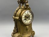 an antique clock sitting on top of a table on a white surface