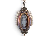 a close up of a necklace with pearls and a picture of a woman