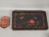 a small tray with a flower design on it next to a small rock