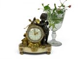 a statue of a boy holding a clock next to a vase of flowers