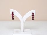 pair of red garnet stone earrings on a white stand