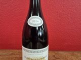 La bouteille de vin est posée sur la table, devant un mur rouge.