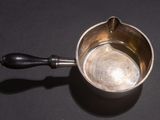 a small metal bowl with a handle on a table