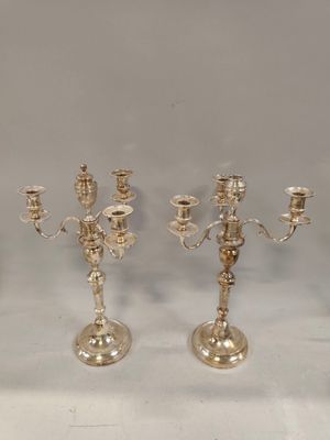 trois chandeliers en argent posés sur une table, sur fond blanc