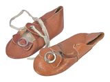 une paire de chaussures de bébé en cuir marron avec des boucles argentées, sur fond blanc