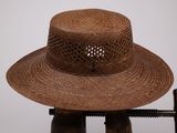 un chapeau marron posé sur un support, avec un pistolet à côté
