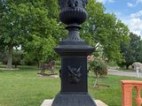a black urn on a pedestal in the middle of a park