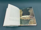 an open book with a picture of a woman laying on a rock