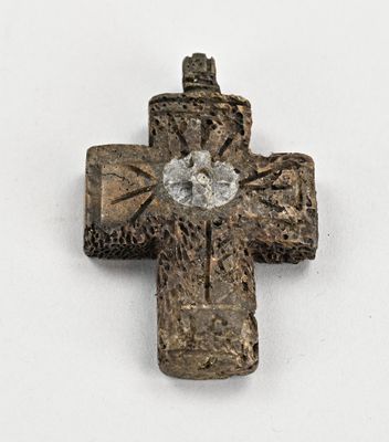 une vieille croix en métal posée sur une surface blanche, avec un diamant au centre