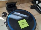 un robot posé par terre à côté d'une bouteille de vin