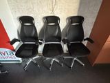 four black office chairs are lined up against a wall