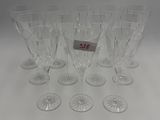 six clear wine glasses are lined up on a white surface