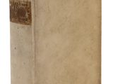 an old book sitting on top of a white table next to a white wall