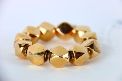une image d'un gros plan d'un bracelet en or sur une surface blanche