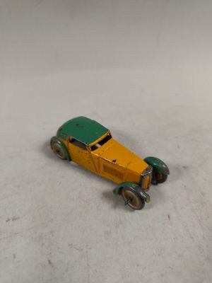 une petite voiture jaune et verte posée sur un sol recouvert de neige