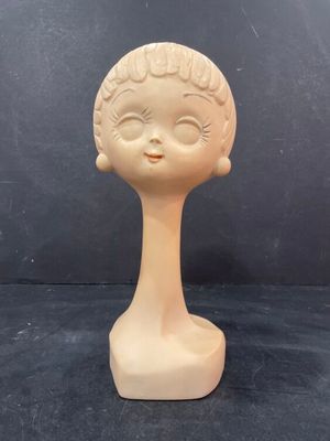 a small doll head on a table with a black background
