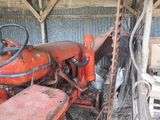 a red tractor that is parked in a barn