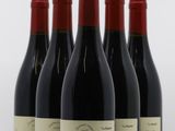 quatre bouteilles de vin rouge sont alignées sur une surface blanche