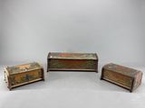 trois morceaux de bois ornés de décorations métalliques, posés sur une surface blanche