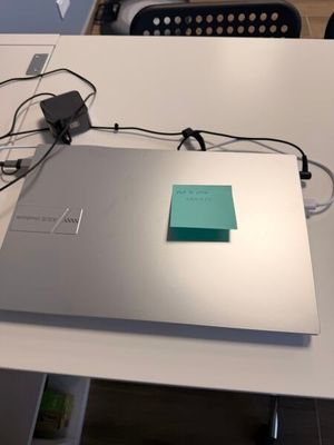 un ordinateur portable posé sur une table, avec des câbles branchés dessus