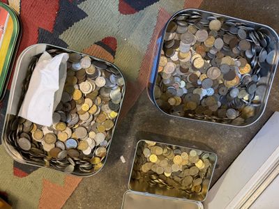 several tins filled with coins sitting on top of a rug