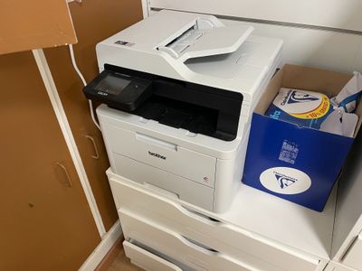 une imprimante blanche posée sur un meuble blanc