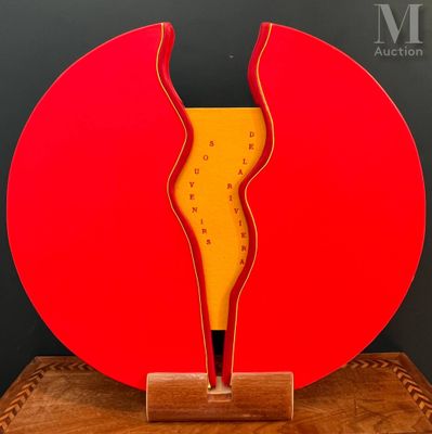 une sculpture rouge et jaune posée sur un socle en bois