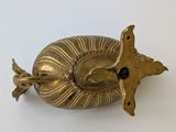 a gold object on a white surface with a bird on it