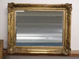 un miroir posé sur une étagère, à côté d'un miroir accroché au mur