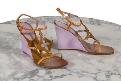 des sandales à talons compensés violettes et beiges posées sur une surface en marbre