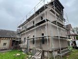 scaffolding on the side of a house with a truck parked in front of it