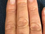 a close up of a person ' s hand with a diamond ring on it