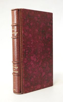 un vieux livre à la couverture rouge posé sur une surface blanche