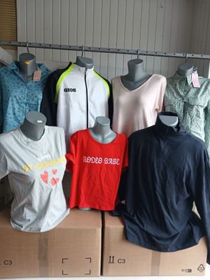 several mannequins of different colors and sizes of shirts in a storage area